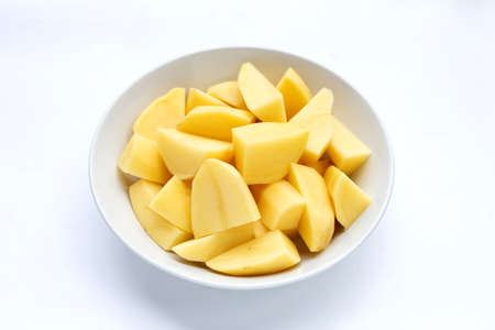 Fresh potato cut into pieces in bowl on white background.の写真素材