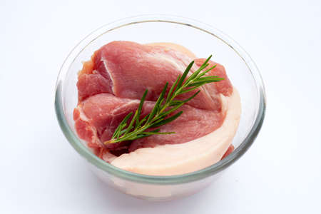 Pork meat in glass bowl with rosemary on white background.の写真素材