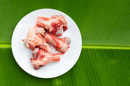 Raw pork bones in white plate on banana leafの写真素材