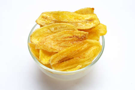 Banana slice chips in glass bowl on white backgroundの写真素材
