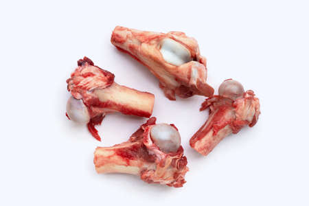 Raw pig bone in white bowl on white background.
