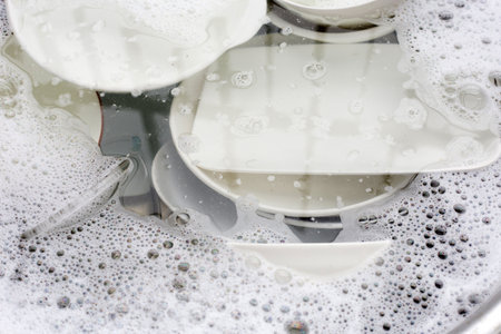 Washing dishes, Close up of utensils soaking in kitchen sink.の写真素材