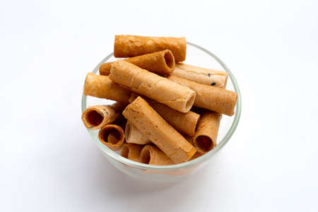 Thai crispy coconut rolls in glass bowl on white background.