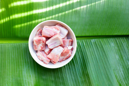 Raw pork ribs in white bowl onbanana leaf background.