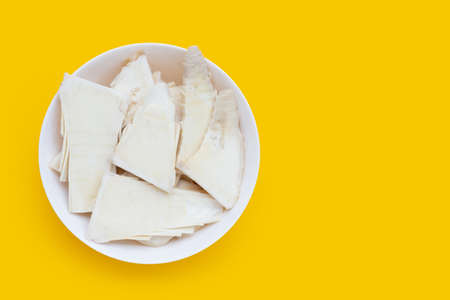 Sliced raw bamboo shoots in white bowl on yellow background.の写真素材