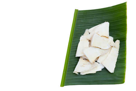 Sliced raw bamboo shoots on banana leaf on white background.の写真素材