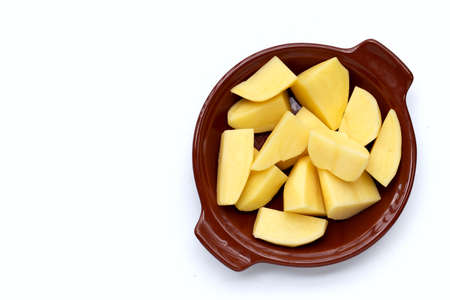 Raw potato cut into pieces in bowl on white background.の写真素材