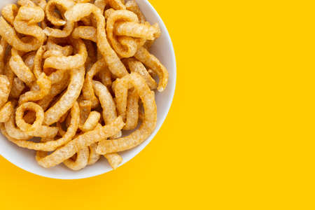 Fried crispy pork rinds in white plate on yellow background.の写真素材