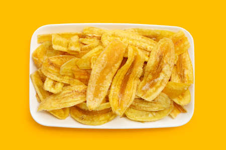 Banana slice chips in white plate on yellow backgroundの写真素材
