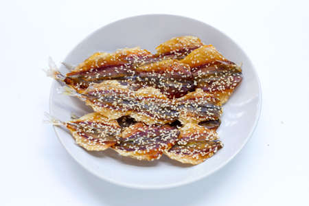 Dried fish with sesame seeds in white plate on white background.の写真素材