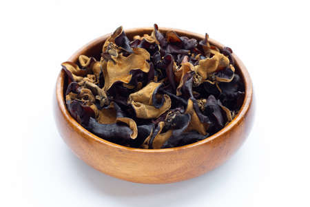 Dried black fungus in wooden bowl on white background.の写真素材