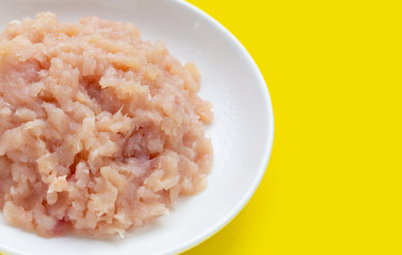 Minced meat of chicken fillet in white plate on yellow background.の写真素材