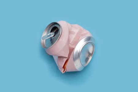 Crumpled pink can on blue background.の写真素材