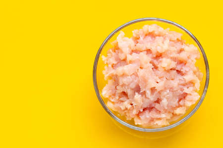 Minced meat of chicken fillet in glass bowl on yellow background.の写真素材