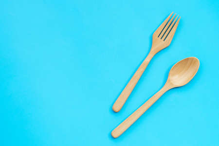 Wooden spoon and fork on blue background.の写真素材