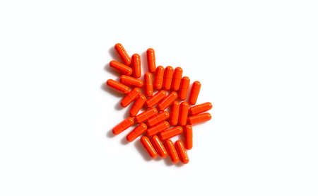 Orange capsule pills on white background.の写真素材