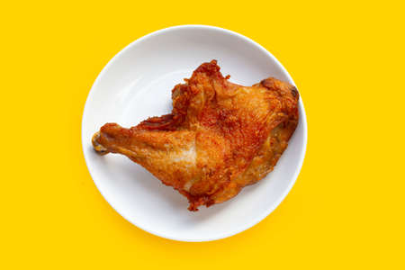 Fried chicken in white plate on yellow background.