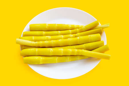 Preserved bamboo shoot in white plate on yellow background.