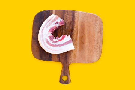 Streaky pork on cutting board on yellow background.の写真素材