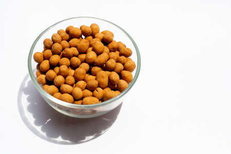 Crispy peanut snack balls in glass bowl on white background.の写真素材