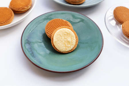 Custard cream sandwich biscuits in plate on white background.
