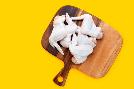 Fresh raw chicken wings on cutting board on yellow background.の写真素材