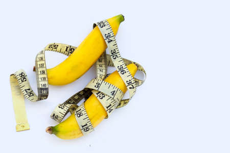 Banana wrapped in measuring tape on white background.
