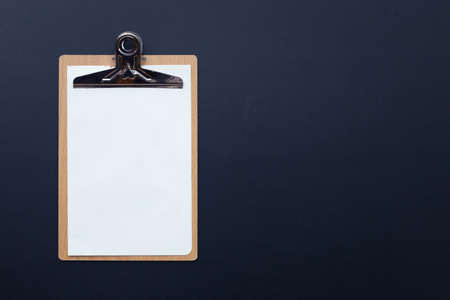 Wooden clipboard with blank white paper on dark background.の写真素材