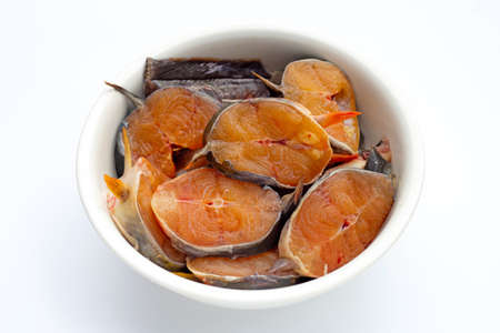 Catfish cut pieces in white bowl on white background.
