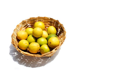 Fresh limes in bamboo basket on white background.