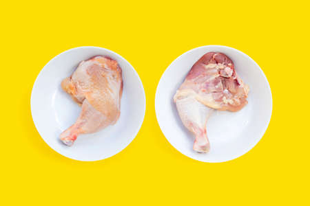 Raw chicken legs in white plates on yellow background.の写真素材