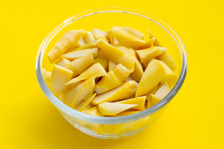 Preserved bamboo shoot in glass bowl on yellow background.