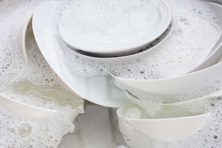Washing dishes, Close up of utensils soaking in kitchen sink.