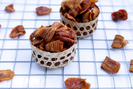 Banana slice chips in bamboo basket on white background.の写真素材