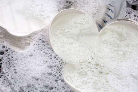 Washing dishes, Close up of utensils soaking in kitchen sink.の写真素材