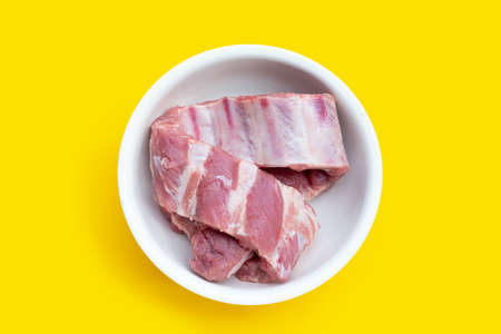 Raw pork ribs in white bowl on yellow background.の写真素材