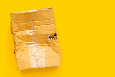 Damaged cardboard box with hole on yellow background.の写真素材
