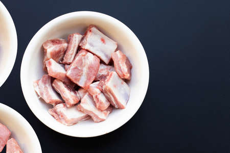 Raw pork ribs in white bowl on dark backgroundの写真素材