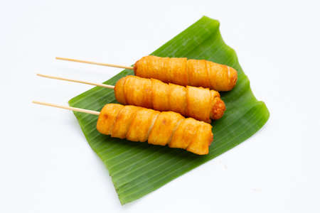 Fried dough snacks wrapped sausage on banana leafの写真素材