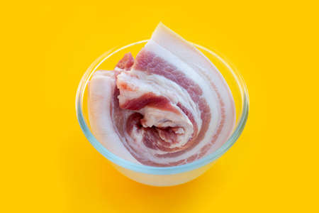 Streaky pork in glass bowl on yellow background.の写真素材