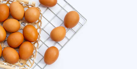 Chicken eggs in bamboo basket on white.