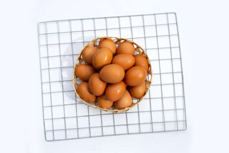 Chicken eggs in bamboo basket on white.