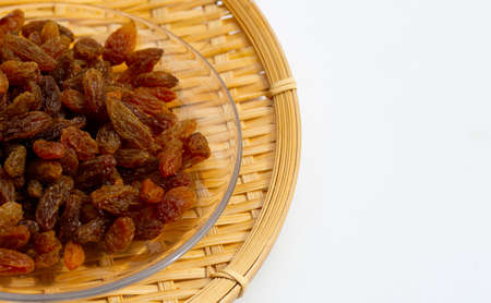 Dried grape raisins in bamboo basket on white background