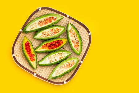 Bitter gourd in bamboo basket on yellow background.