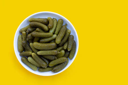 Pickled gherkins or cucumbers in white plate on yellow background.の写真素材