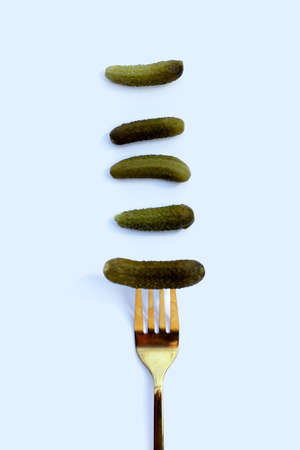 Pickled gherkins or cucumbers  in a fork on white background.の写真素材