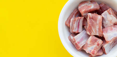 Raw pork ribs in white bowl on yellow backgroundの写真素材