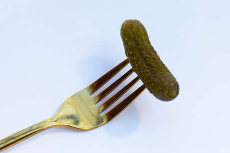 Pickled gherkin or cucumbers in a fork on white background.の写真素材