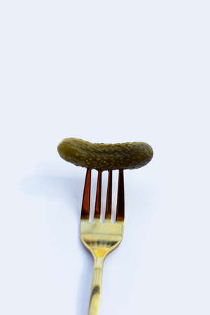 Pickled gherkin or cucumbers in a fork on white background.の写真素材