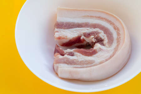 Streaky pork in white bowl on yellow background.の写真素材